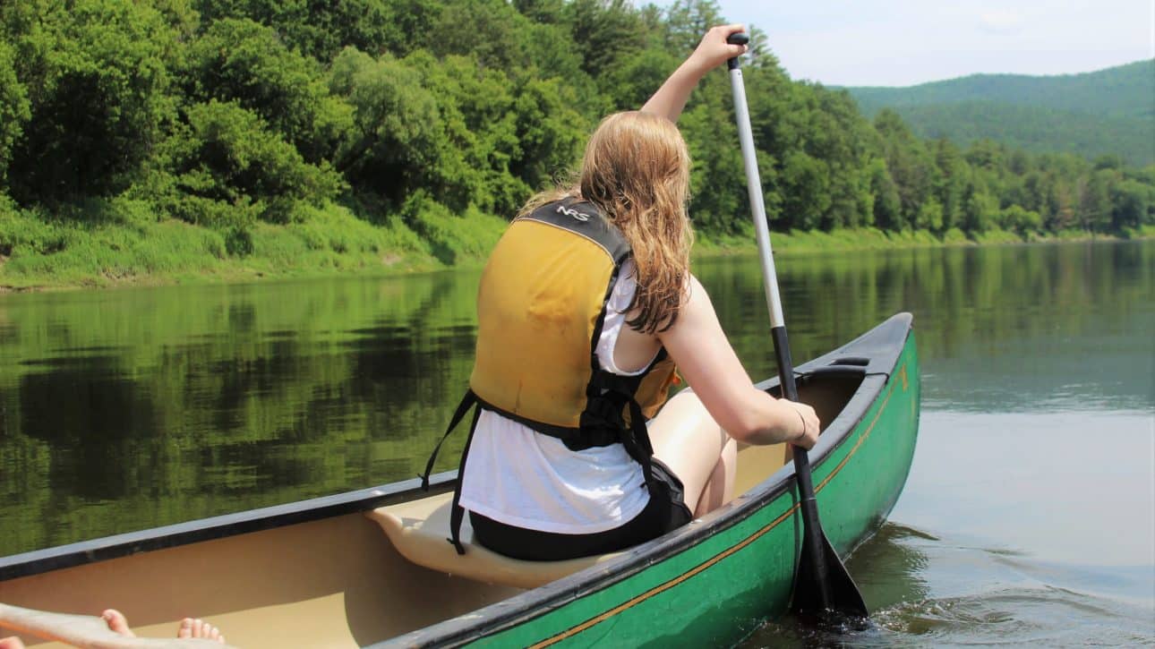 Teenager rowing canoe town a quiet New Hampshire river